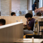 A student at Ƶ studies on a laptop in the newly renovated dining area of the Lowry Center.
