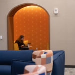 A student doing schoolwork in a yellow theme lounge on the second floor of Lowry Center at Ƶ.